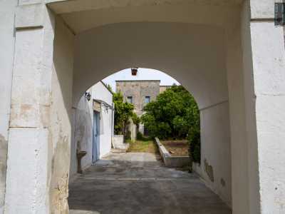 Attraverso un arco tufaceo bianco accediamo al cortile